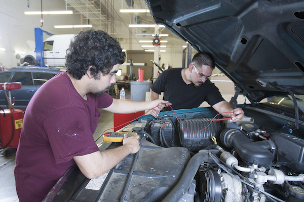 auto students working together to jumpstart a vehicle