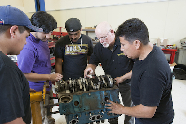 auto students and instructor examining an engine
