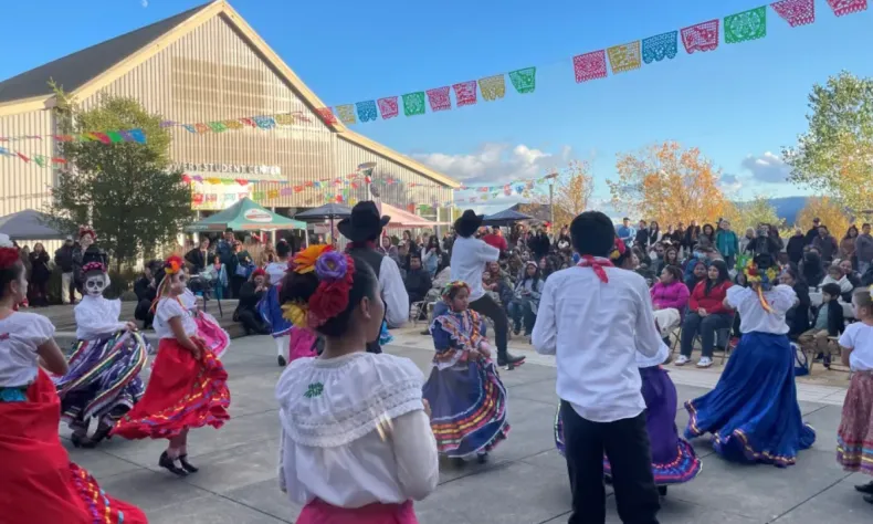 Colorful Dia de lost Muertos young dancers in Pomo Plaza with blue sky