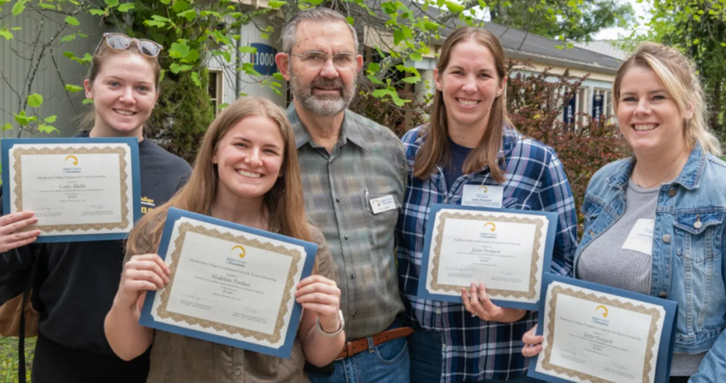 Four women and one man smiling and holding scholarship award certificates