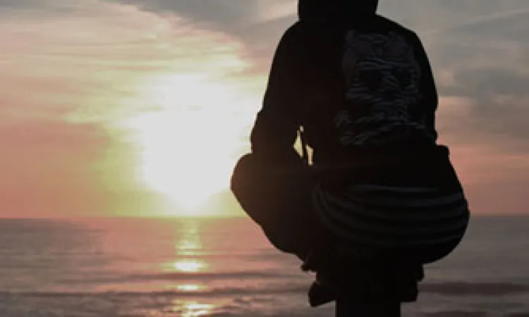 person sitting looking at sunset