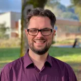 man with glasses and purple shirt